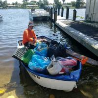 Clean up volunteer on his boat at the Lake Clarke Shores Boat Ramp with bags of trash