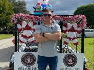Entry 66, An individual in front of a decorated trailer with candy canes, garland, and inflatables. 