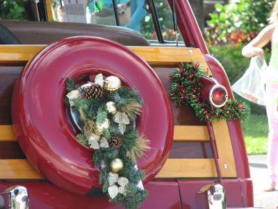 Image of a wreath and ornaments on the back of a vintage red car, 
