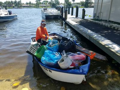 Clean up volunteer on his boat at the Lake Clarke Shores Boat Ramp with bags of trash