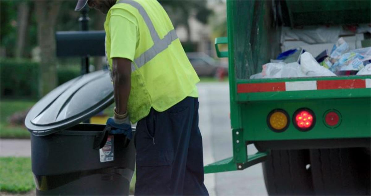sanitation worker collecting a can