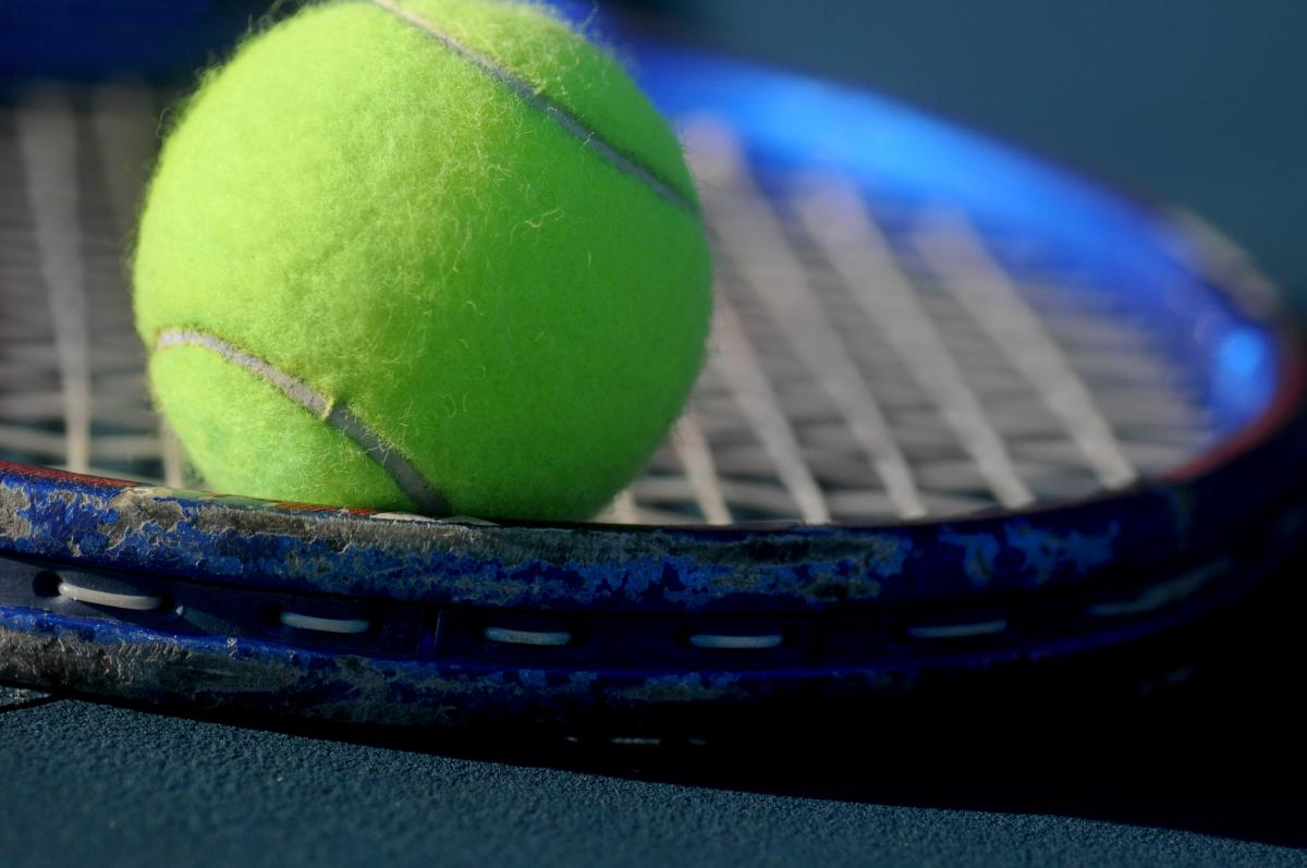 Tennis Ball resting on Tennis racket