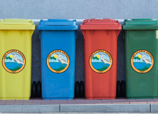 Four trashcans (yellow, blue, red, and green) with the Lake Clarke Shores logo on them. 